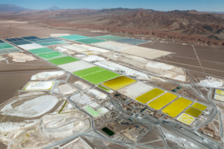 Vast pools of brine are shown in the desert in various hues of blue, green and yellow