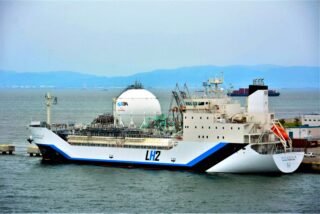 A large white tanker with an LH2 logo on its side is docked in Japan.